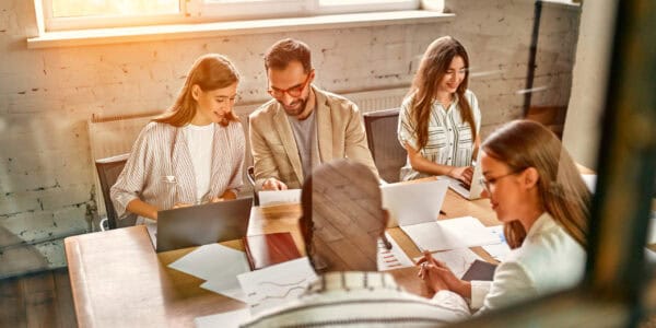 Young professional team. Group of young modern people in elegant casual clothes are brainstorming while sitting behind glass wall in creative office